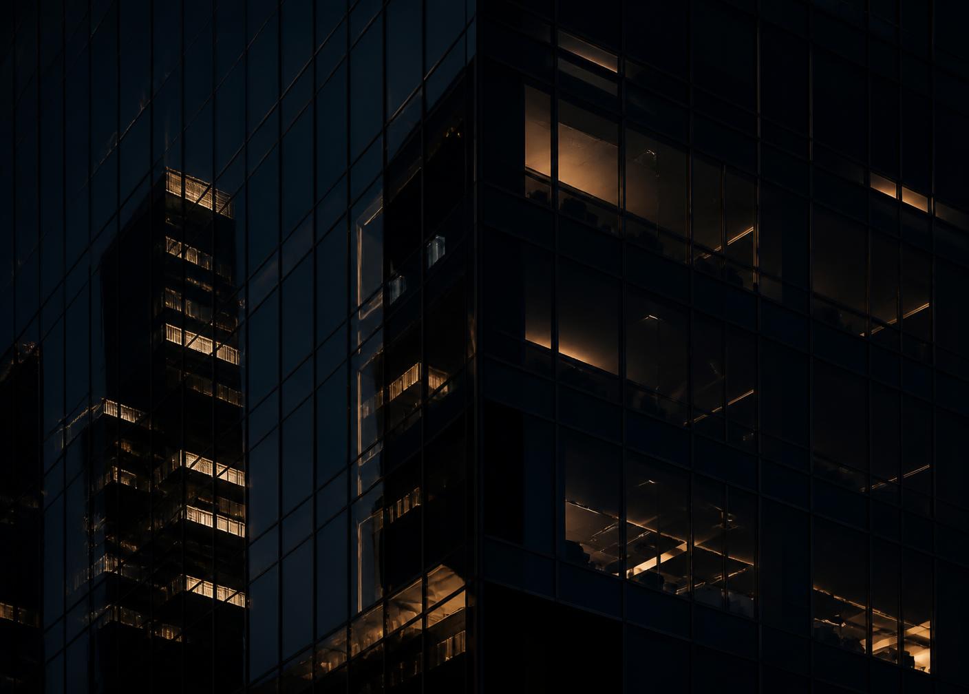 Detail of a modern glass office tower at night, lit from within